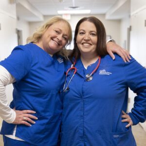 Two nurses standing next to each other and smiling.