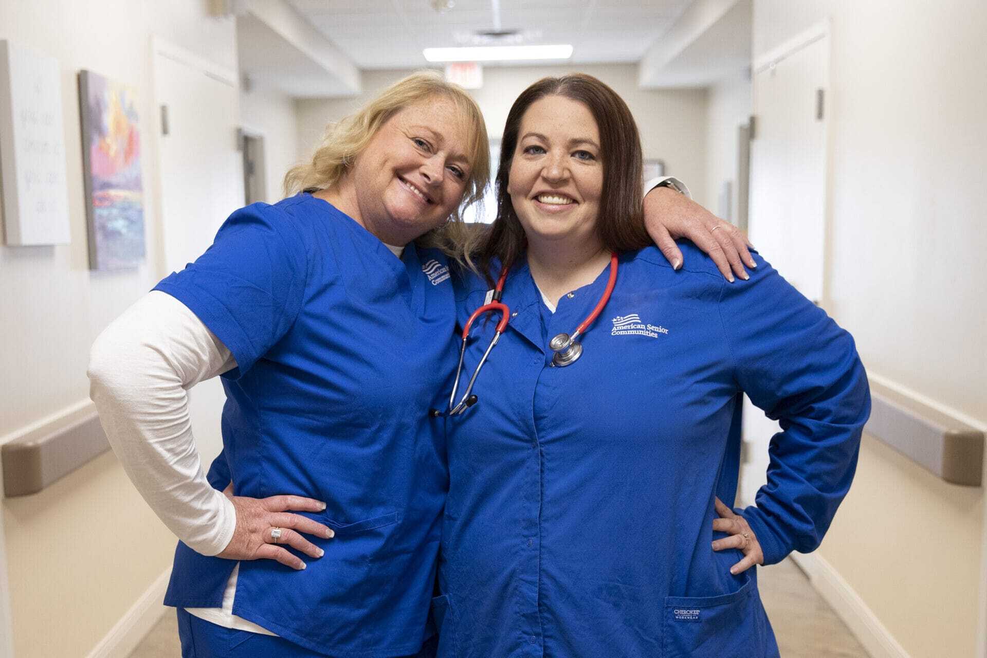 Two nurses standing next to each other and smiling.