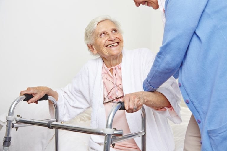 Nurse helping senior citizen patient in nursing home getting up