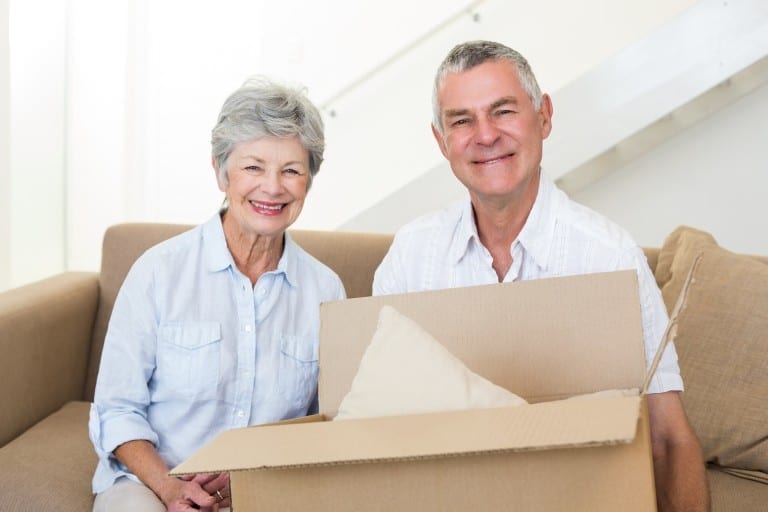 Cheerful senior couple moving into new home smiling at camera