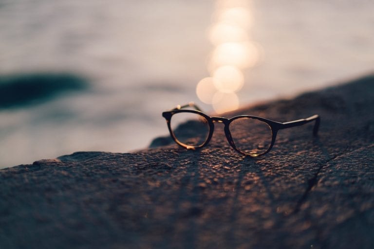 Glasses on rock during sunset