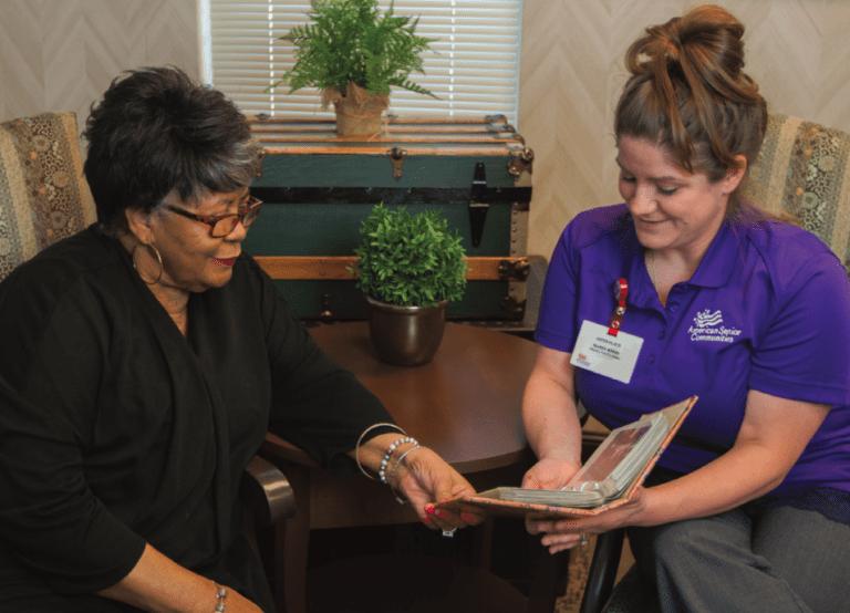 a caregiver and resident looking at a photo album