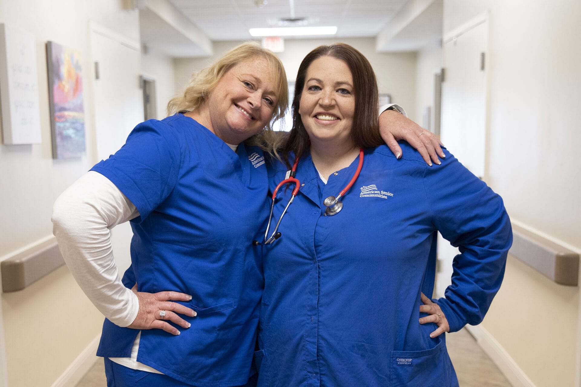 Two nurses standing next to each other and smiling.
